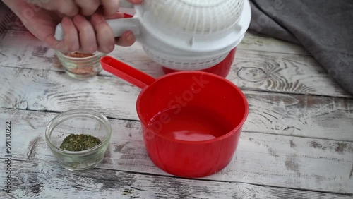 Making homemade adyghe cheese in the cheese making mold. Turning the hot product for further pressing and sprinkling the other side with dried herbs and salt  photo