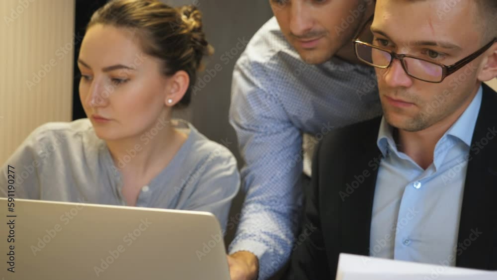Young coworkers examining statistical data information on laptop at office. Professional managers work on business development sitting at table. Colleagues planning strategy for corporate project Young coworkers examining statistical data information on laptop at office. Professional managers work on business development sitting at table. Colleagues planning strategy for corporate project