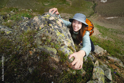 In summer, a young woman goes rock climbing while hiking in the mountains. Female rock climber on the mountain