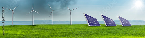 Windräder und Solarzellen auf einer Grünen Wiese in einer hügeligen Landschaft