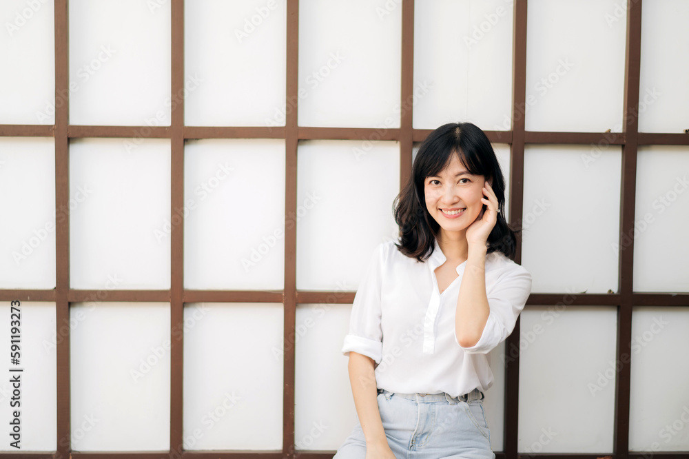 Portrait beautiful young asian woman happiness sitting on wooden grid wall, Happy female is smiling on wooden grid wall, wellness people concept. Portrait beautiful young asian woman happiness sitting on wooden grid wall, Happy female is smiling on wooden grid wall, wellness people concept.