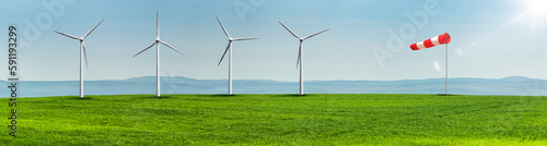 Windräder auf einer Grünen Wiese in einer hügeligen Landschaft