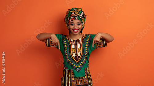 Beautiful black woman in african clothing pointing at herself