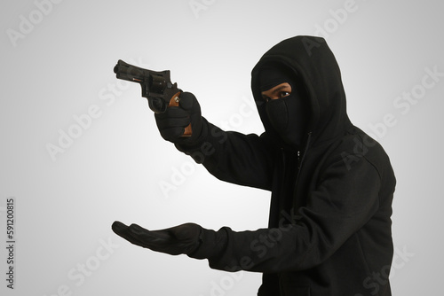 The male thief forcibly demanded the victim's money and valuables at gunpoint
