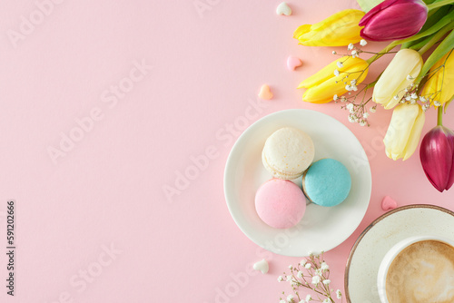 Women's Day concept. Flat lay photo of cup of coffee plate with macaroons small hearts bunch of colorful tulips and gypsophila flowers on pastel pink background with blank space