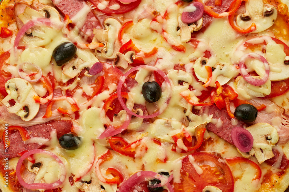 Freshly baked pizza with smoked sausages, red pepper, mushrooms, onion and olives served on wooden background with tomatoes, sauce and herbs. Food delivery concept. Restaurant menu Freshly baked pizza with smoked sausages, red pepper, mushrooms, onion and olives served on wooden background with tomatoes, sauce and herbs. Food delivery concept. Restaurant menu