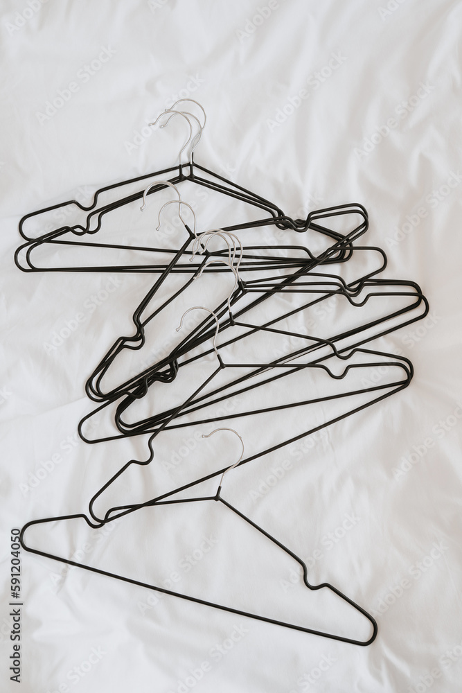 Fototapeta premium Lots of hangers on white linen cloth. Minimalist fashion, wardrobe, clothes concept. Flat lay, top view