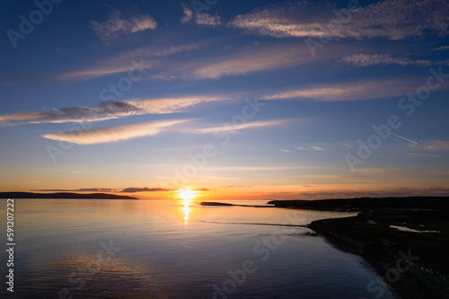 Stunning sunset over Galway bay and silhouette of the coast line. Blue cloudy sunset sky. Warm and cool color tone. Ireland. Aerial view.