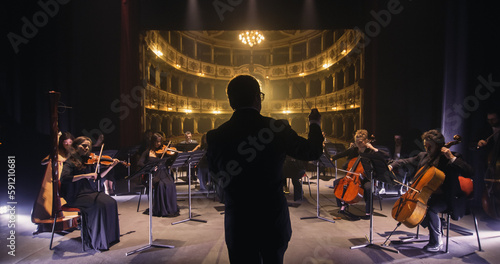 Cinematic Back View of Professional Conductor Directing Symphony Orchestra with Performers Playing Violins, Cello and Trumpet on Classic Theatre with Curtain Stage During Music Concert
