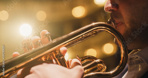 Cinematic Closeup of the Hands and Mouth of a Male Trumpet Player Reading a Music Sheet and Playing his Instrument. Professional Musician Rehearsing Before the Start of a Big Jazz Show photo