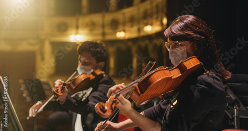 Cinematic Close Up Shot of Professional Symphony Orchestra Violin Player Playing on Classic Theatre with Curtain Stage during Music Concert. Performers Playing Music for Audience