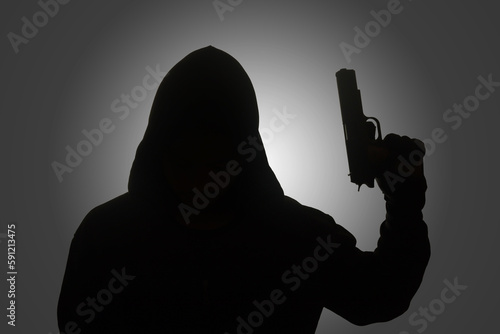 Konstfotografi Mysterious man wearing black hoodie holding a pistol, shooting with a gun