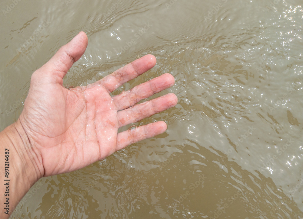 The hand of a young man is touching the flowing water. The hand of a young man is touching the flowing water.