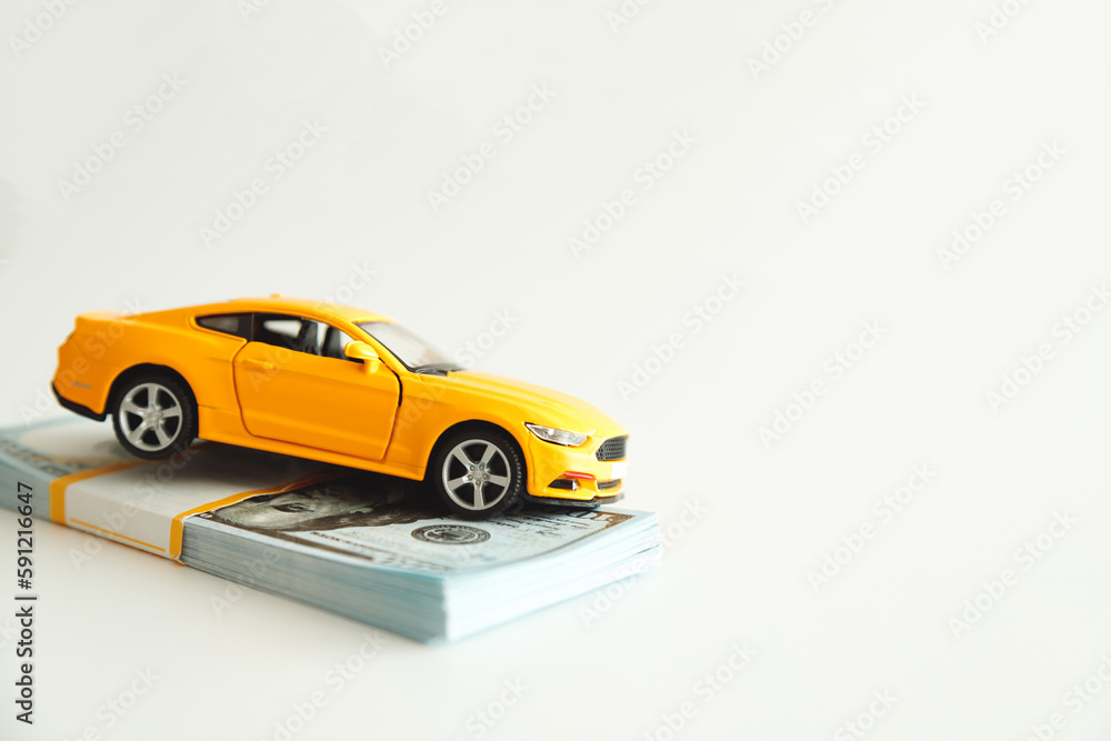 Toy Car Hanging on a Stack of Money on a White Background. Concept Car Expenses, loan payment