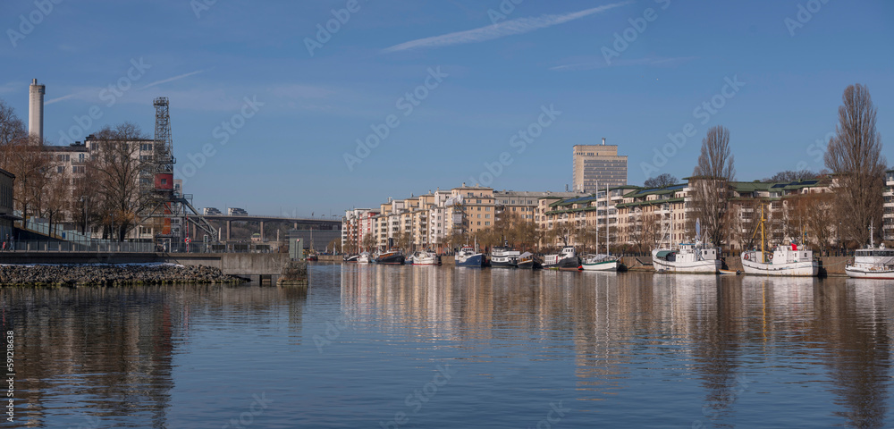 Waterfront apartment house and boats at a pier in the bay Hammarby sjö, a sunny spring day in Stockholm