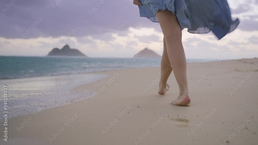 Barefoot woman walking by scenic beach leaving footprints in white sand ...
