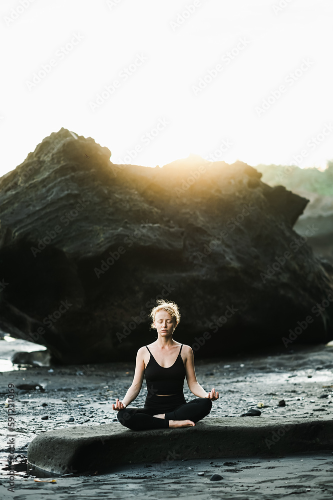Young, beautiful girl - doing yoga and meditation on the beach.