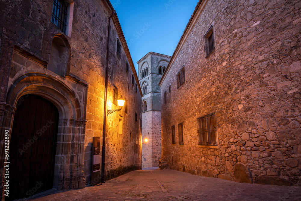 Street in the old town of Trujillo, Cáceres, Spain, at dawn with streetlight lighting and a church tower in the background