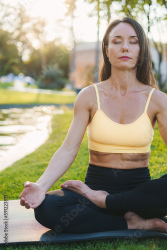 Beautiful brunette woman wearing sportive clothes, outdoor doing yoga easy seat pose, sukhasana posture.relax breathe easy seat pose, healthy lifestyle concept