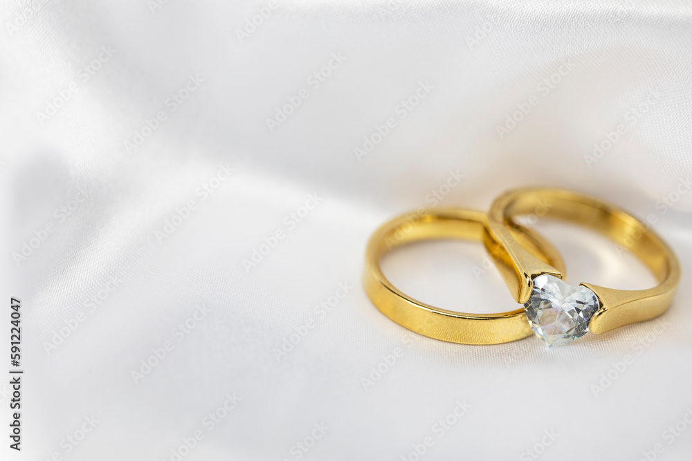 Festive wedding background with two gold rings with diamond on white satin material. Copy space. Festive wedding background with two gold rings with diamond on white satin material. Copy space.