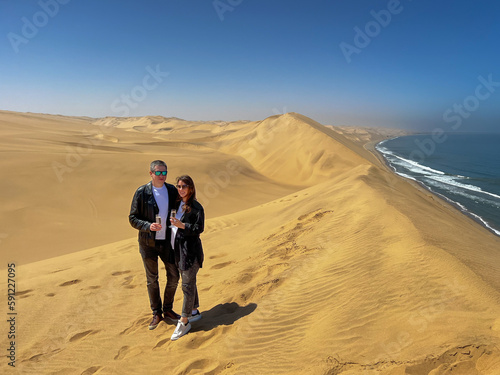 Young couple - man and woman stands at sandy dunes. Sandwich Harbour in Namibia.
