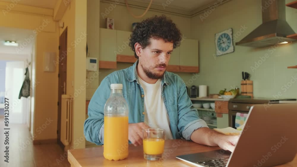 Young man with laptop at the table in the kitchen Young man with laptop at the table in the kitchen