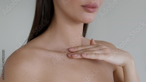 Skincare concept. Young unrecognizable woman with bare shoulders touching smooth and healthy skin, caressing neckline photo