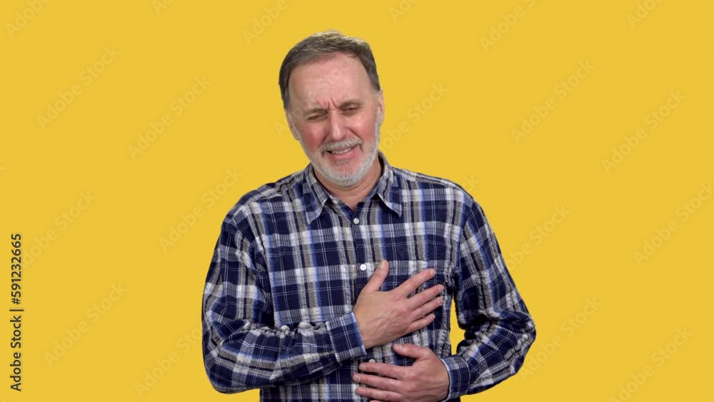Mature senior caucasian man is having a heart pain. Male touching his chest because of heart attack. Isolated on orange. Mature senior caucasian man is having a heart pain. Male touching his chest because of heart attack. Isolated on orange.