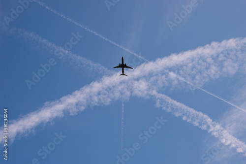 Airplane in a blue sky with crossing vapour trails