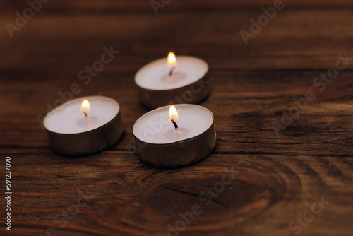 Three paraffin floating candles on a wooden table.
