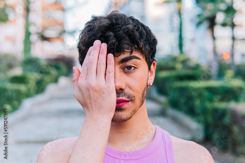 Man from the lgbt collective with makeup, covering his face with his hand in protest against homophobia photo