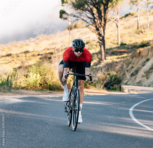 Young athlete riding a bicycle on an empty road. Cyclist in helmet and goggles exercising outdoors.