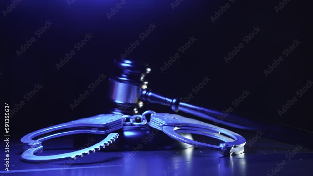 Handcuffs with judge gavel. Red and blue light from a police flashers