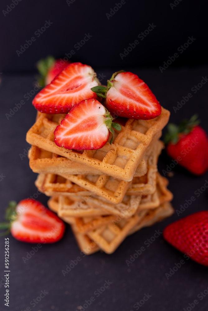 Belgian waffles with strawberries on a black background.
