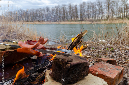 Picnic on the river bank. sausages are fried on a fire. photo