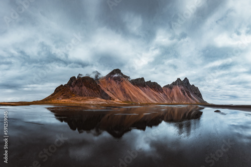 Famous Stokksnes mountains on Vestrahorn cape in southeastern Icelandic coast. The epic sky reflected in the clear water. Iceland island. Landscape photography