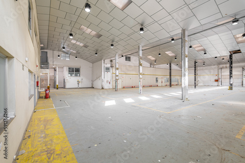 Parking garage with lights, light-colored walls, metal beams and ceiling prepared for renovation into a party hall. The concept of spacious premises before renovation © Pavel