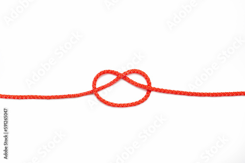 Red rope with a knot not completely tied on a white isolated background. Red nylon rope with an untied knot in the center. The concept of an uncoupled task or a knot of a problem to be solved photo