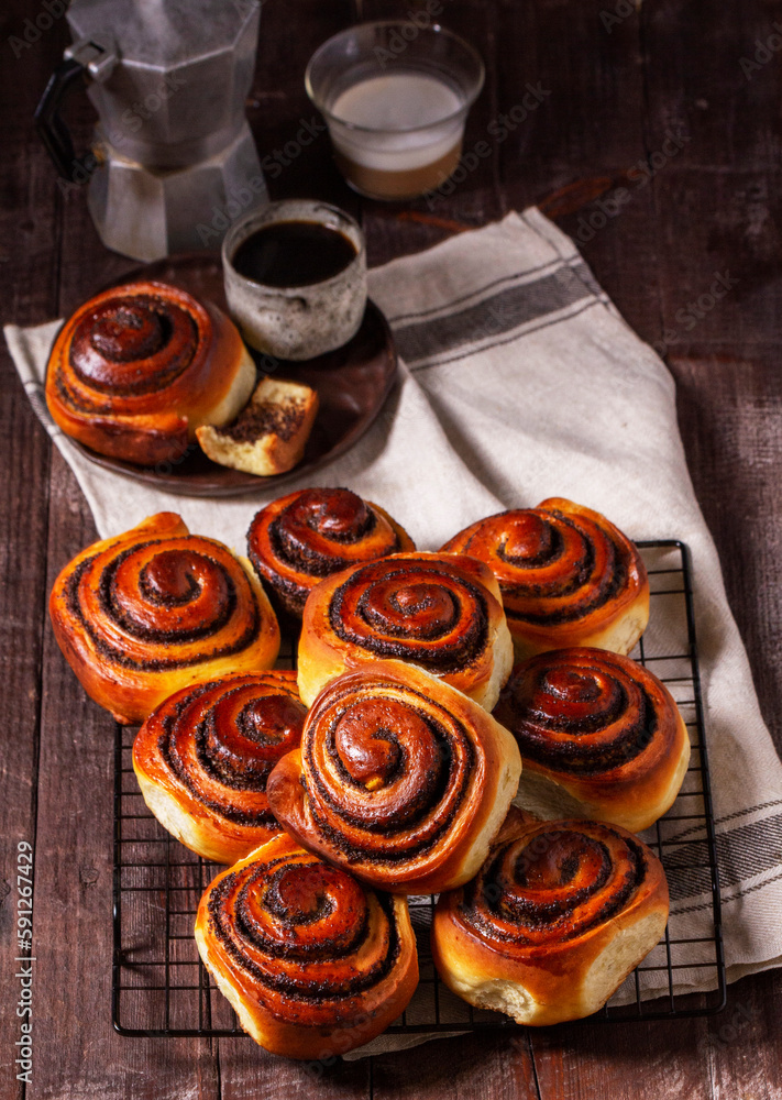 Yeast dough cinnabons with poppy seeds, raisins and candied fruits, served with coffee. Rustic style.