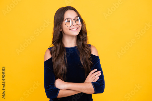 Happy face, positive and smiling emotions of teenager girl. Teenager kid crossed arms with confidence isolated on yellow. Confident teen child girl crossed hands.