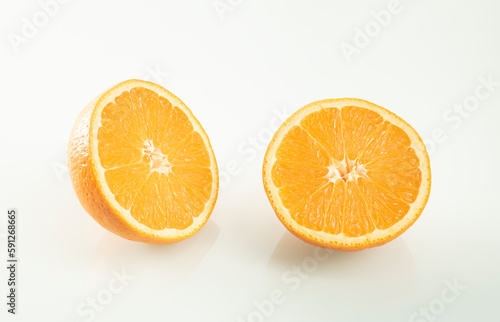 Two halves of an orange with reflection on a white mirror background