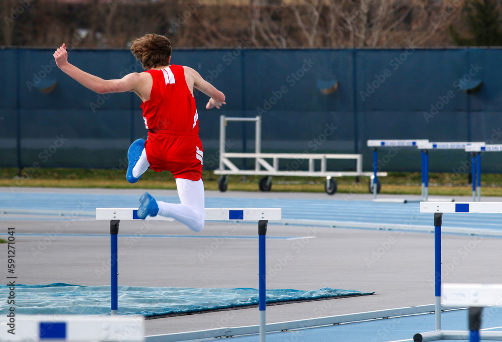 Runner jumping over a track hurdle during a race Stock Photo Adobe Stock