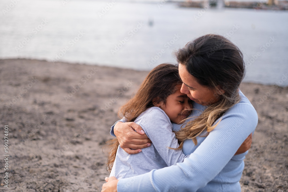 Little girl hugging her tired mother after a long walk by the sea. Concept: motherhood, childhood, growth