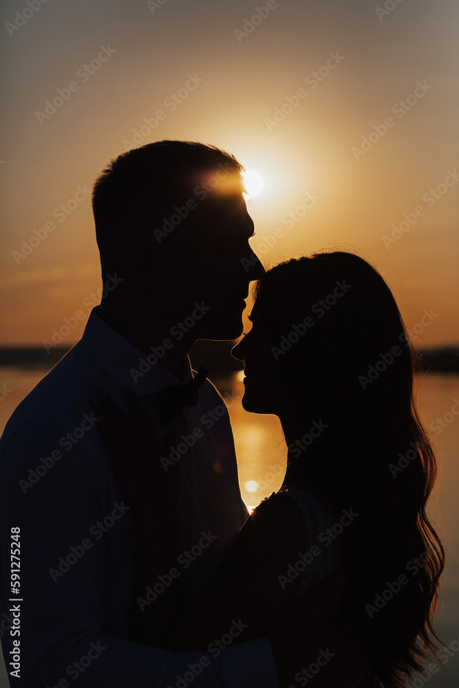 Beautiful shade loving happy couple hugging at sunset on the seashore in warm summer day. Beautiful shade loving happy couple hugging at sunset on the seashore in warm summer day.