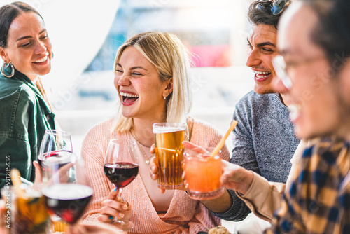 happy friends having fun drinking cocktails at bar restaurant- Young group of people enjoying happy hour together holding fancy drinks sitting at pub table-Life Style party concept with guy and girls 