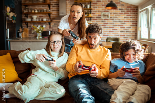 Young family playing video games together in the living room on a gaming console © Baba Images