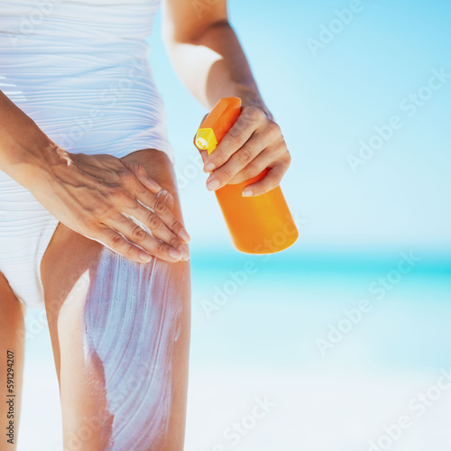 Closeup on young woman applying sun block creme on beach