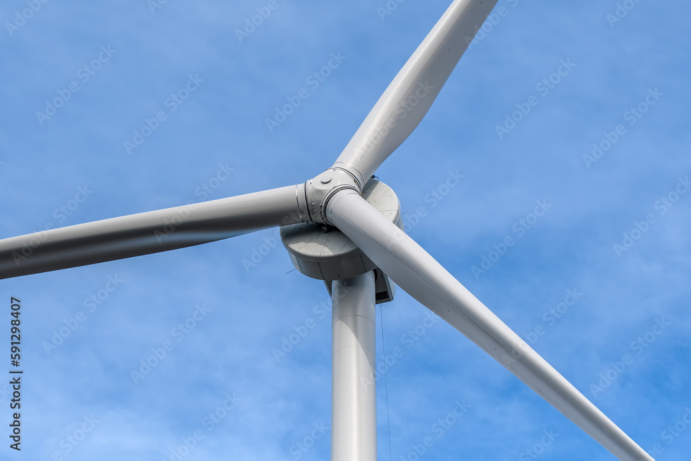Closeup of a large wind turbine, looking up at an angle. Blue sky behind with thin cloud. Closeup of a large wind turbine, looking up at an angle. Blue sky behind with thin cloud.