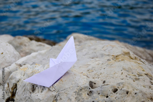 Paper boat on the rocks by the sea, travel concept