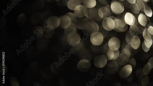 Slow diagonal movement of silver bokeh. The overflow motion of light defocused circles from corner to corner. Abstract moving silvery bokeh lights 4K background.